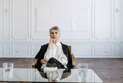 A woman siting on the chair in black suit